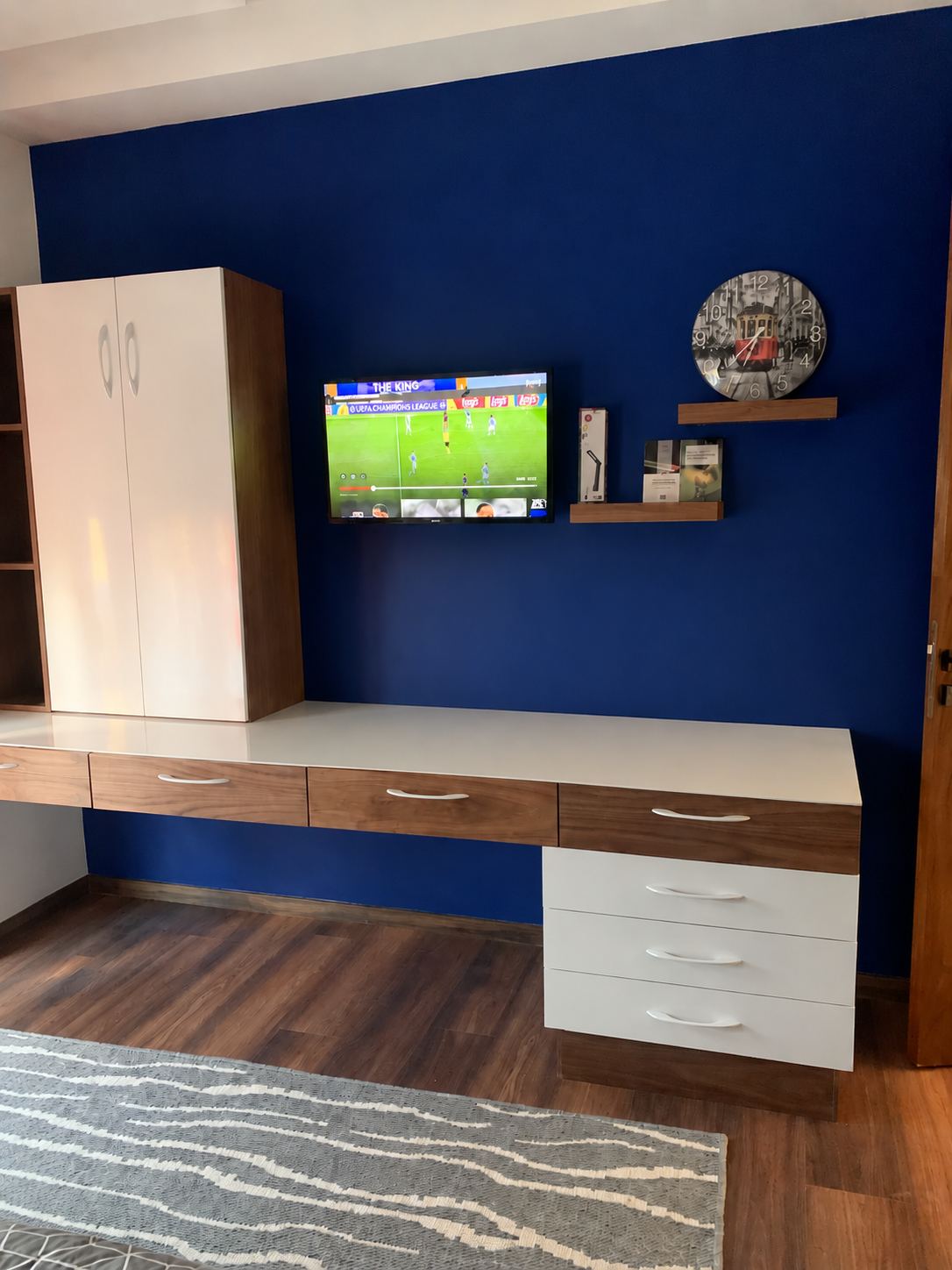 Plan de travail sur mesure toute longueur avec tiroirs blancs et armoire assortie, contre un mur bleu, sur parquet foncé.
