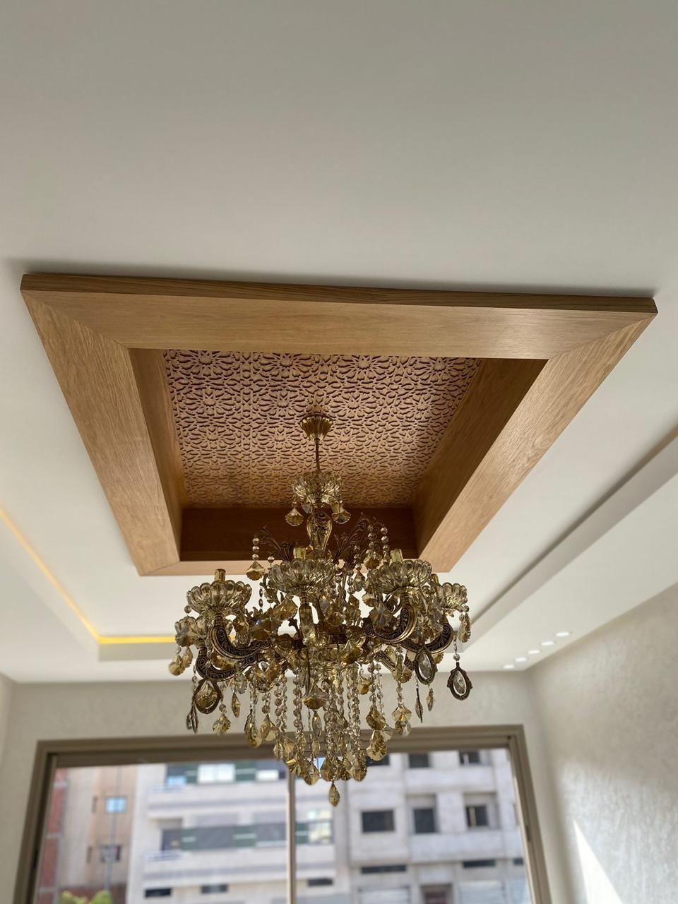 Caisson de faux plafond en bois avec panneau central ajouré finement sculpté, autour d'un lustre en cristal.