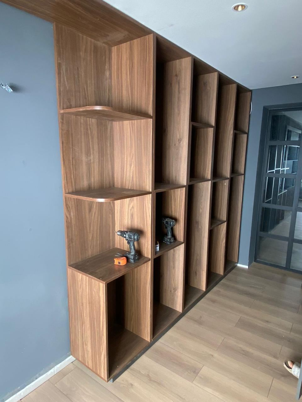 Bibliothèque murale sur mesure à casiers de tailles variées en bois, avec retour d'angle et étagères ouvertes.