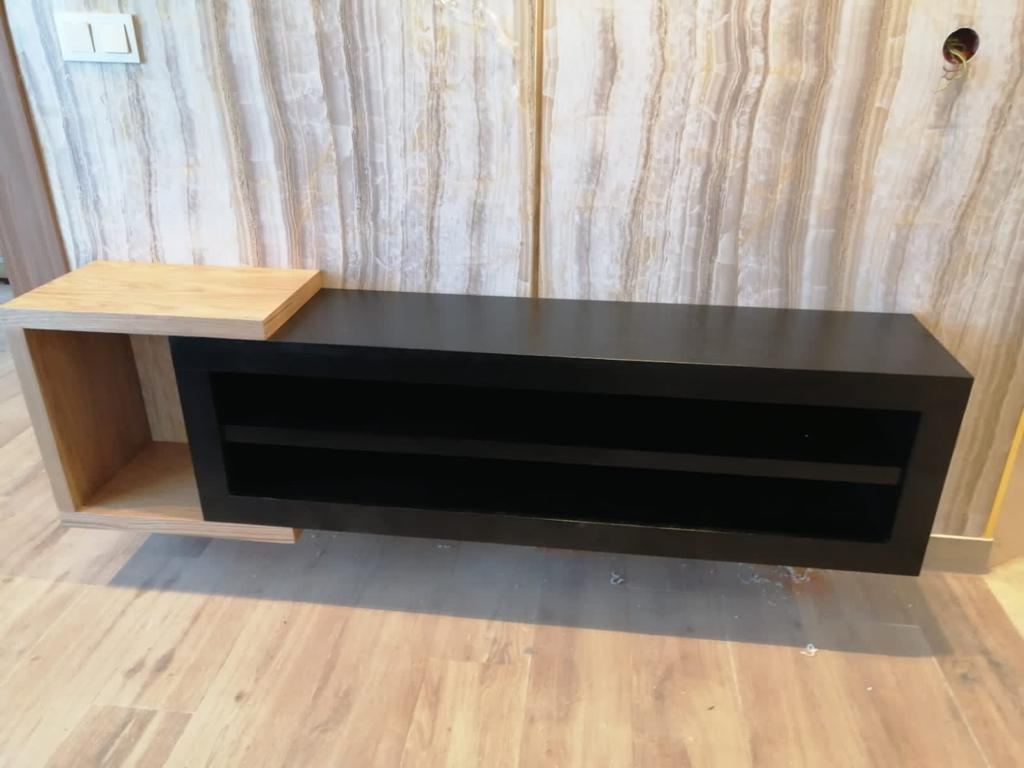 Meuble TV bas sur mesure en bois teinté foncé avec niche ouverte, devant un mur en pierre claire veinée.